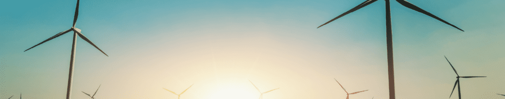 Photograph of wind turbines with sunrise on the horizon